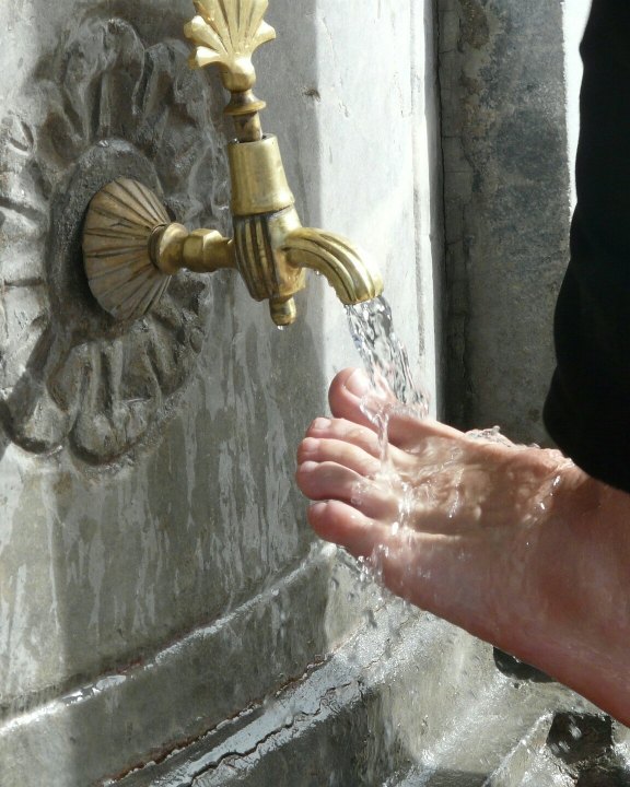 Ein Fuss wird an einem Steinbrunnen mit klarem Wasser abgespült